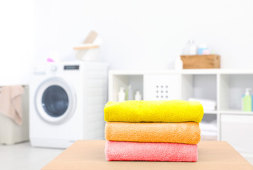 Colorful clean towels on table in laundry room, space for text