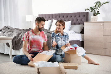 Young couple opening parcels in bedroom at home