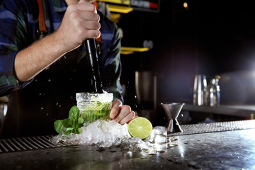 Barman making Mojito cocktail at counter in pub, closeup. Space for text