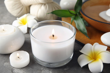 Beautiful spa composition with candles and flowers on grey background