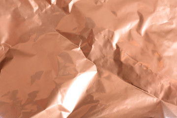 Crumpled rose gold paper as background, closeup view