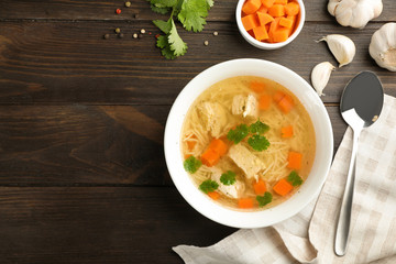 Homemade chicken soup served on wooden table, top view with space for text