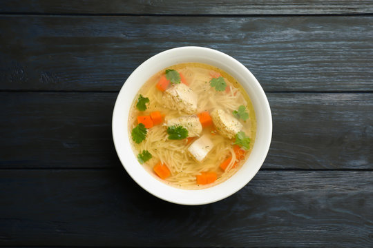 Dish with fresh homemade chicken soup on wooden  background, top view