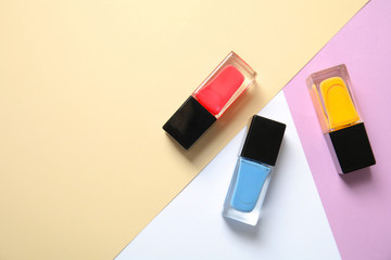 Bottles of nail polish on color background, top view with space for text