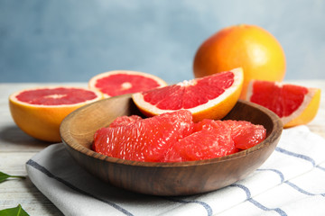 Composition with plate of grapefruits on table against color background