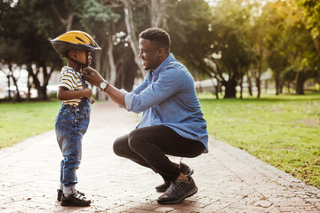 Father puts his son a helmet for riding bike