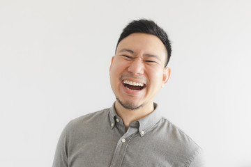 Happy and laughing face of ordinary man in grey shirt. Concept of charming laugh.