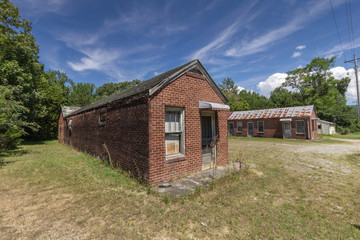 Front of an abandoned red brick motel with blue skies and green grass