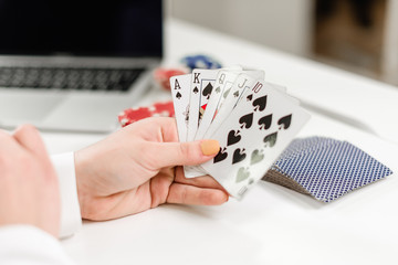 female hands betting and playing cards online on laptop in the office, winning money in internet or mobile casino