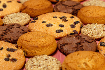 Various shortbread and oatmeal cookies with flakes and raisins on a wooden background.