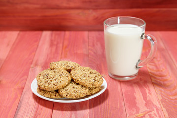 Oatmeal cookies and a glass of milk on a wooden background.