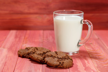 Oatmeal cookies and a glass of milk on a wooden background.