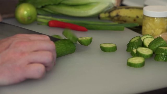 Male hands slicing a mini cucumber.
