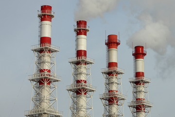 Four red-white pipes with white steam against a clear sky - modern systems of cleaning of harmful emissions