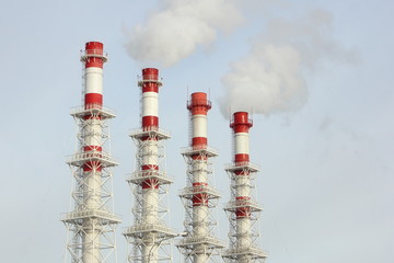 Four red-white pipes with white steam against a clear sky - heat power engineering technology