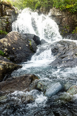Waterfall in mountains. Rapid flow in river. Water in rocks, trip along river.