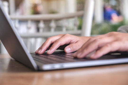 Closeup image of woman's hands using and typing on laptop keyboard on the table