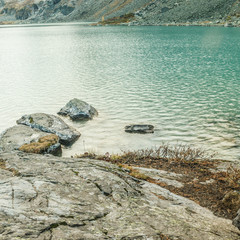 Stone shore of a mountain lake. Turquoise water of the river
