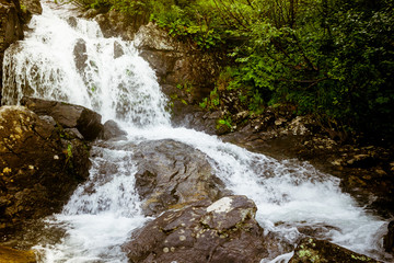 Fototapeta premium Waterfall in mountains. Rapid flow in river. Water in rocks, trip along river.