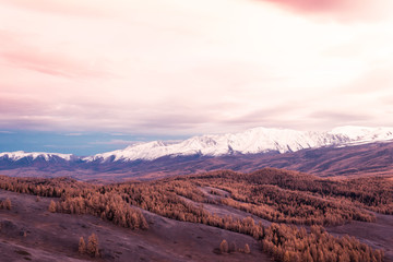 Pink and purple clouds over mountain range. Sunset or dawn in mountains in autumn. Hiking trip to valley of mountains.