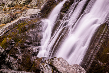 Waterfall in rocks. Fast mountain river