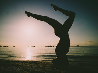 Silhouette Young Woman Practicing Yoga On The Beach At Sunset
