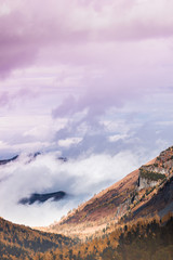 Fototapeta premium Pink clouds over mountain range. Rocks under snow on horizon. Sunset in mountain valley