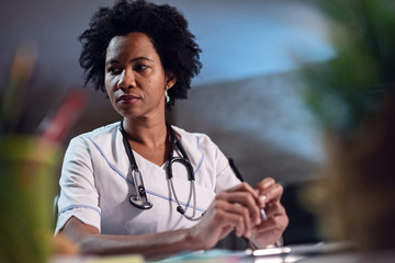 Portrait of pensive African American nurse at her desk.