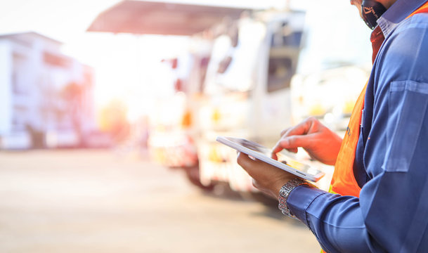 Truck drivers hand holding tablet checking the product list,Driver writing electronic log books,spot focus.