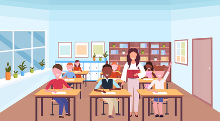 woman teacher reading book during lesson mix race pupils sitting desks education concept modern school classroom interior horizontal flat