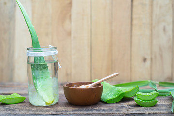 Fresh aloe vera stem and gel on wooden table, skin therapy concept