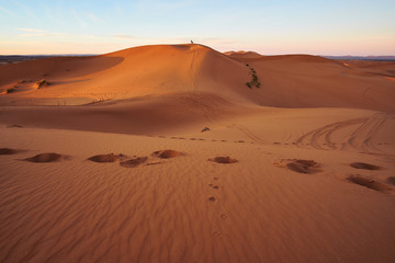 Fototapeta na wymiar Two people standing on the sand dune during sunrise in Merzouga desert Morocco Africa