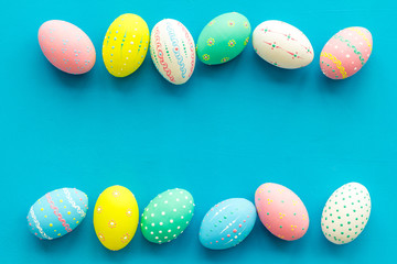 Easter composition. Decorated pastel Easter eggs on blue background top view copy space