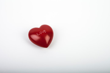 Red stone heart with love sign on white background