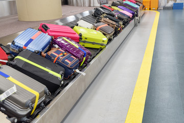 Bright green, pink and blue suitcases on luggage conveyor belt