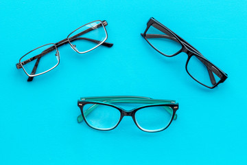 Set of glasses with transparent lenses on blue background top view