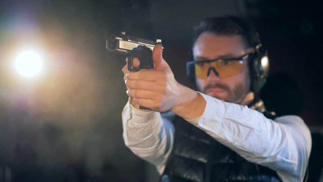 A person fires a handgun at a range, close up.