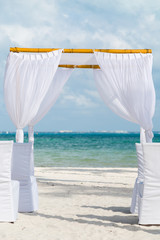 A white wedding alter on a white sand beach in Cancun, Mexico.