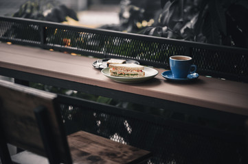 Sandwich and hot coffee on wood bar