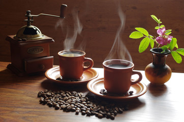 Two cups of hot coffee, from which comes steam.