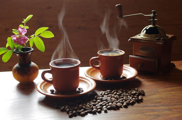 Two cups of hot coffee, from which comes steam.