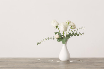 eucalyptus twigs and roses  in  vase on white background