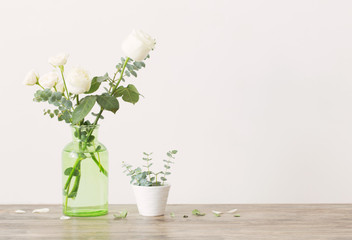 eucalyptus twigs and roses  in  glass vase on white background