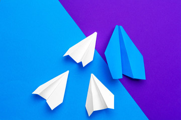 white paper airplane on a blue and purple paper background