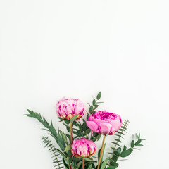 Bouquet of pink peonies, hypericum and eucalyptus branches on white background. Flat lay, top view