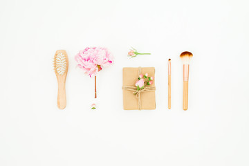 Hairdresser composition of pink peony with hairbrush, tassel and gift box on white background. Flat lay, top view