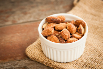 Close up Almonds with salted and Roasted in the white cup put on the sackcloth and wood floor, the great snack 