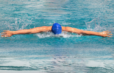 Female swimmer is swimming in butterfly stroke during competition in to the pool