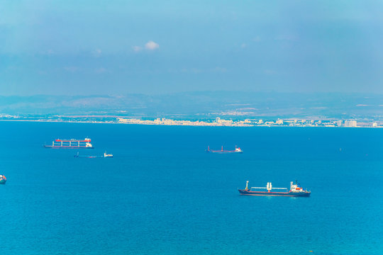 Cargo ships at mediterranean sea with city of Akko at background, Israel