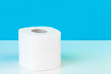 Toilet paper isolated on white table with blue background. Cleaning concept product